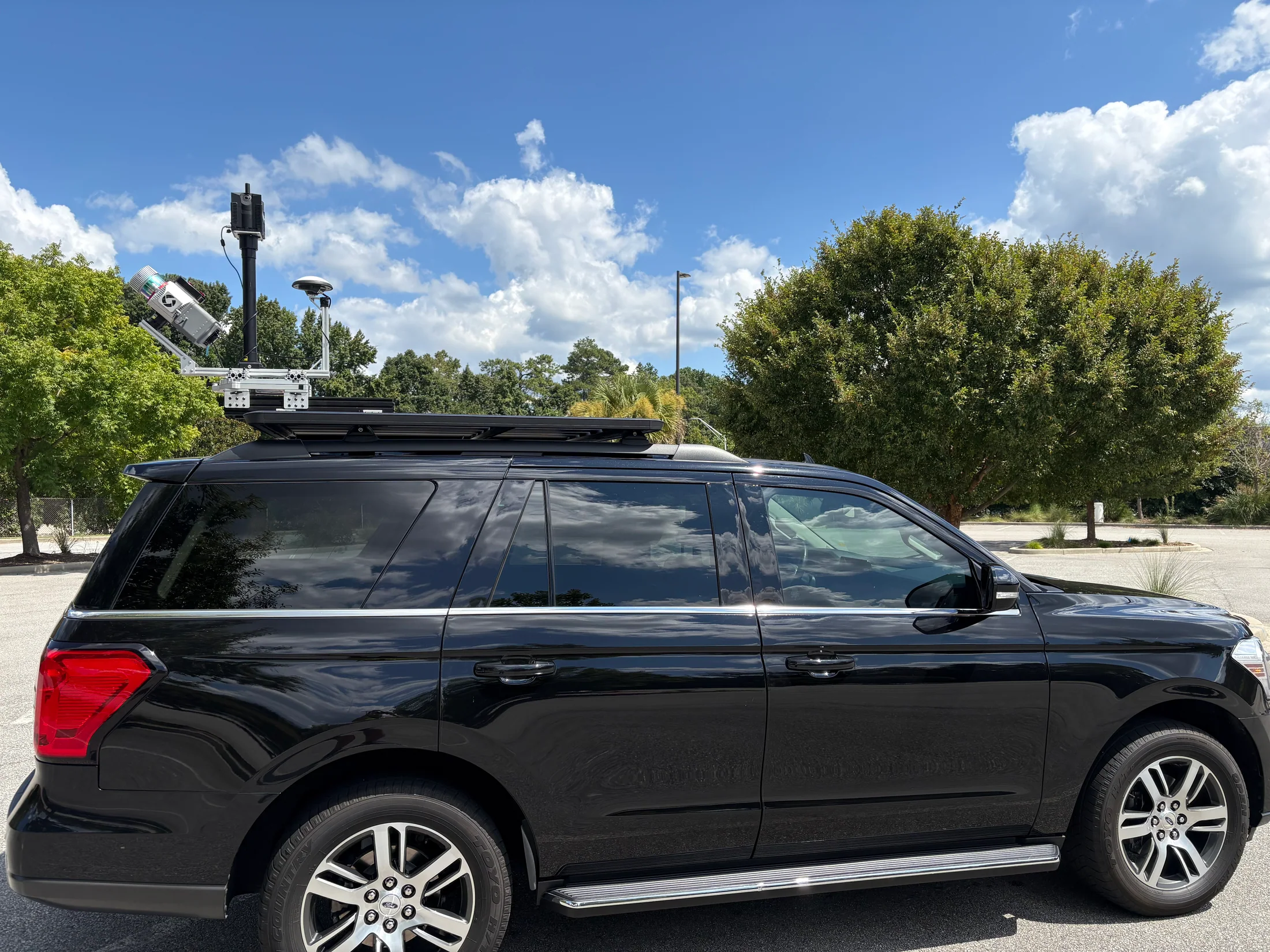 Vehicle-mounted LiDAR scanning rig on a black SUV in the field