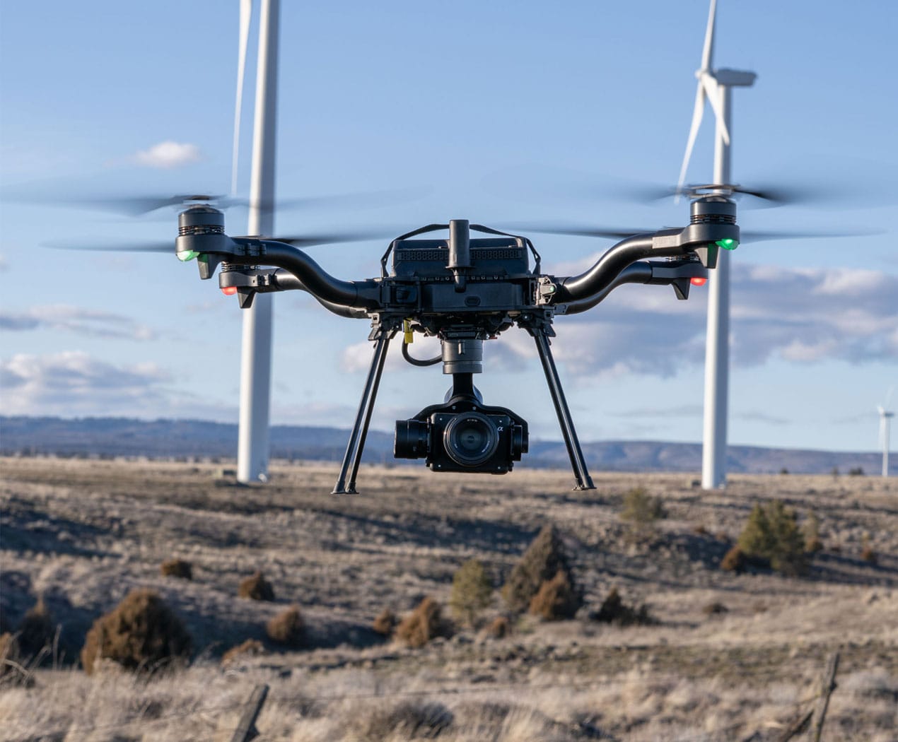 Freefly Astro carrying a Sony camera in flight near wind turbines