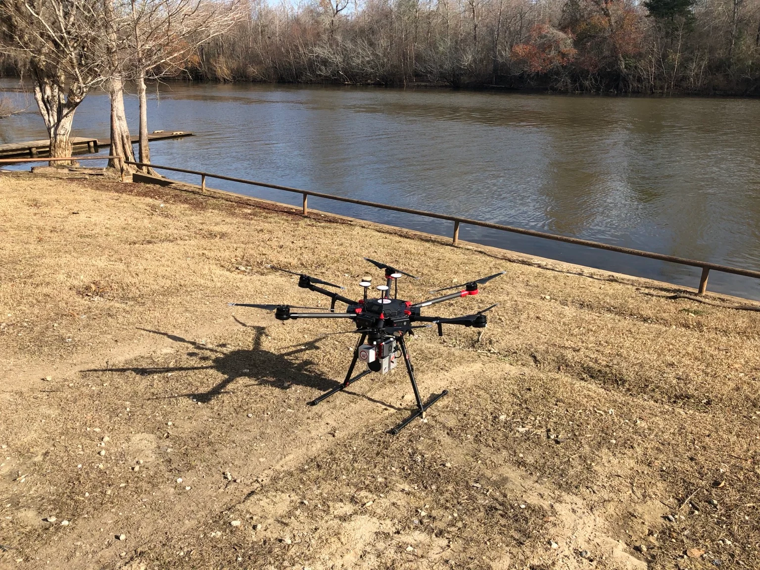 UAV with a LiDARUSA sensor mounted beneath it on the ground beside a river